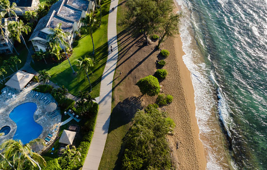 Overhead view of a beachfront resort with pool and a path along the beach.