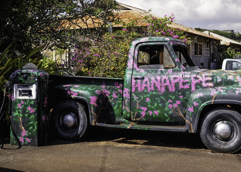 Old truck in Kauai that has been painted with flowers and the name of the town Hanapepe.