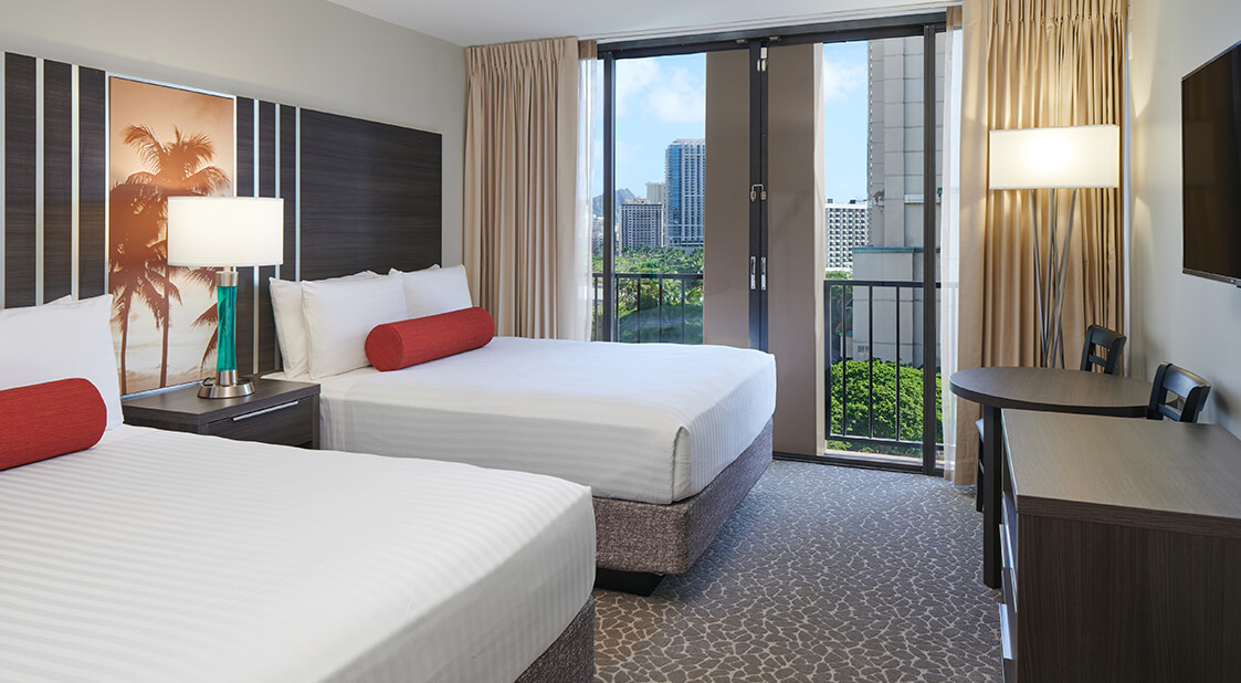 Room with 2 beds, lamps, TV, and balcony.