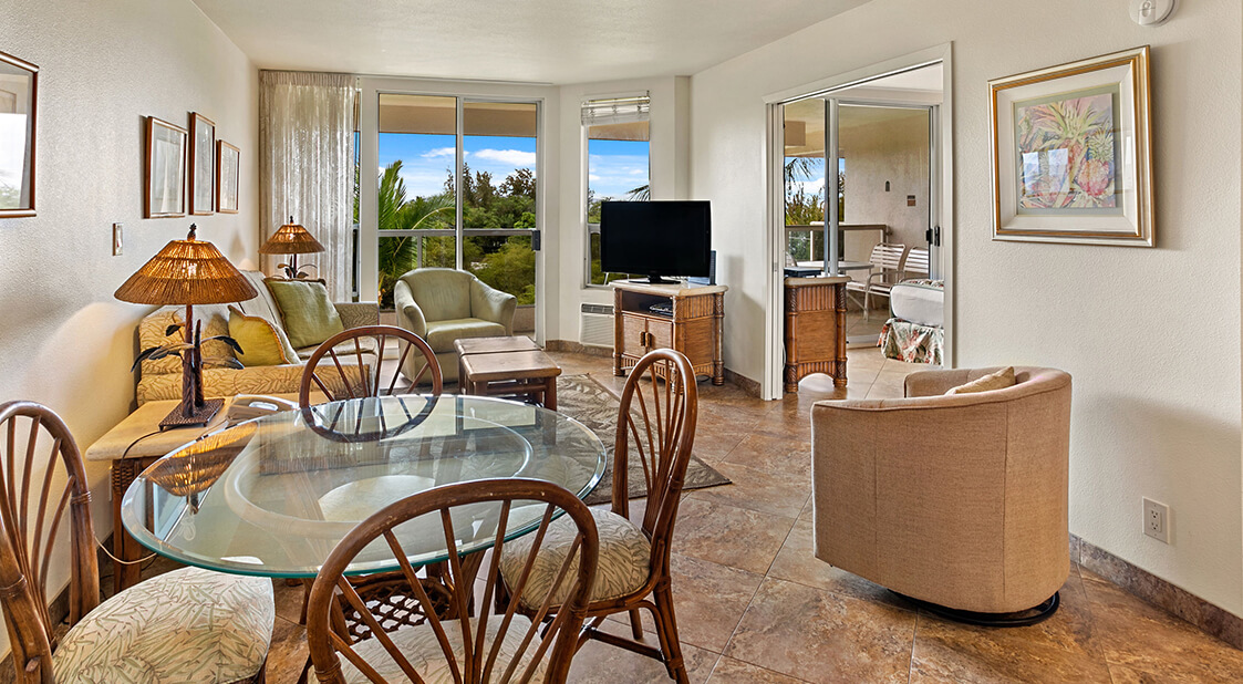 Living room with a couch, coffee table, TV, dining area, and balcony.