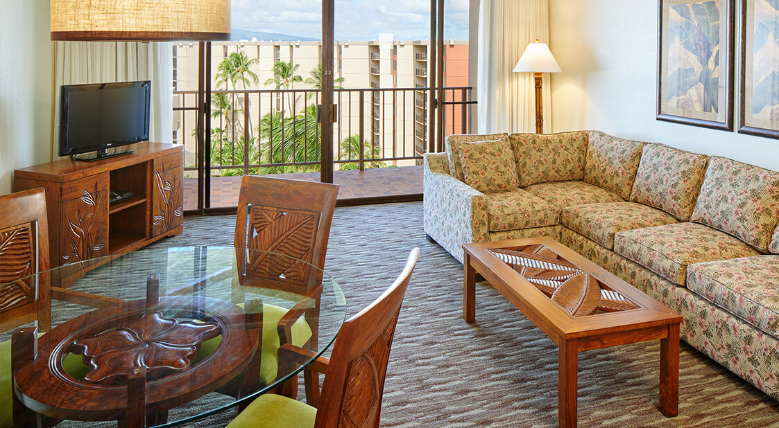 Living room with a couch, coffee table, TV, dining table, and balcony.