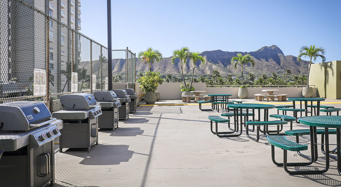 Large outdoor deck with barbecues and picnic tables.