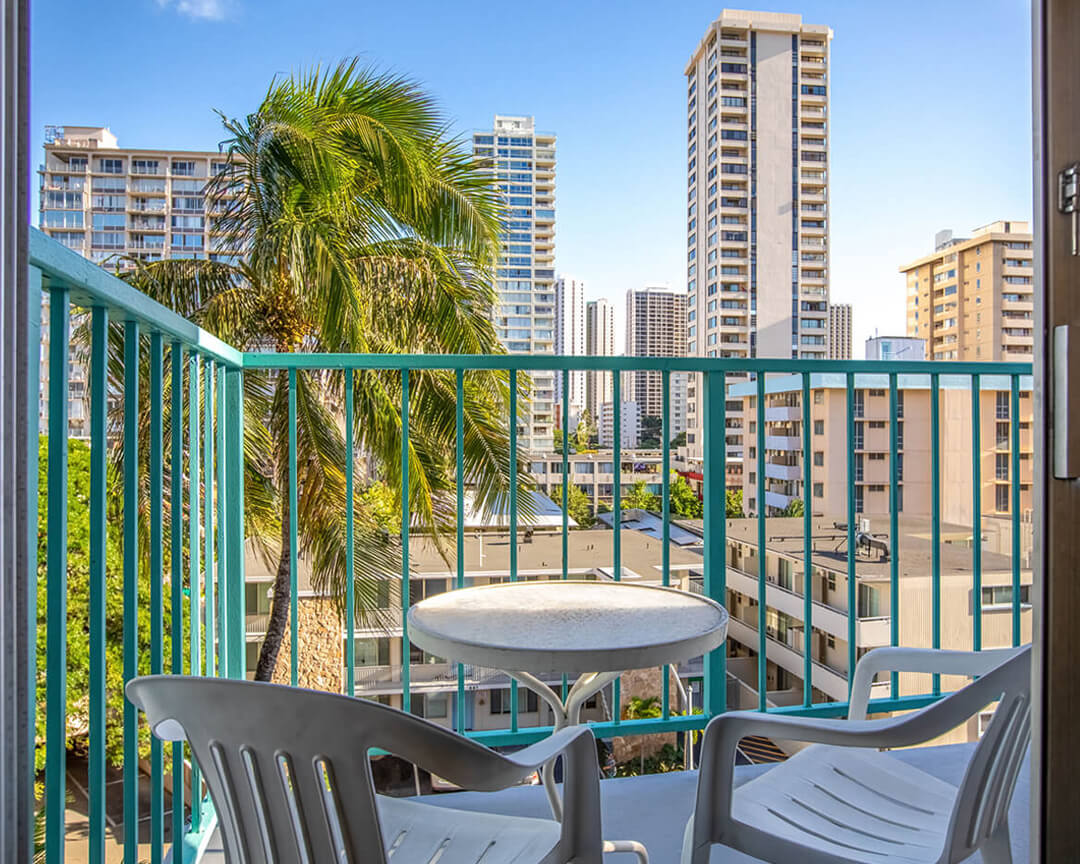 Balcony with two chairs and small table with city view.