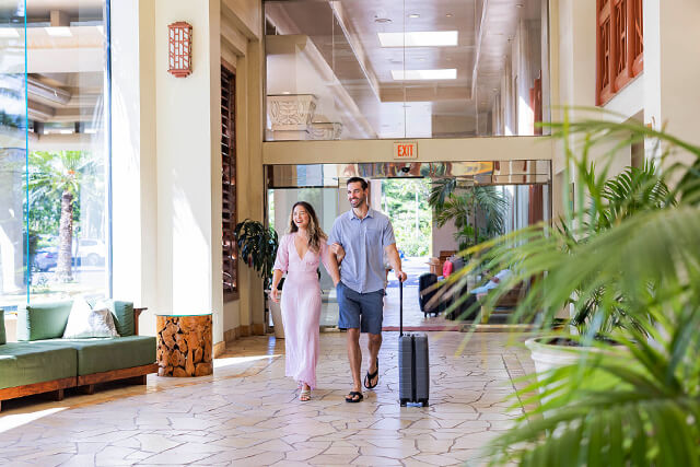 Husband and wife walking with their luggage in the hotel lobby