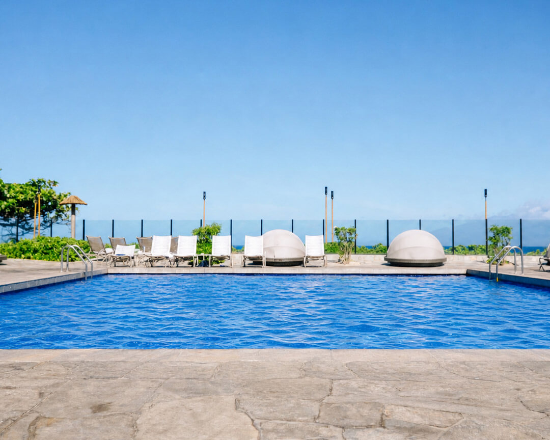 Property pool with sun loungers and ocean view.