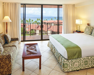 Room with a bed, lamp, and balcony with ocean view.