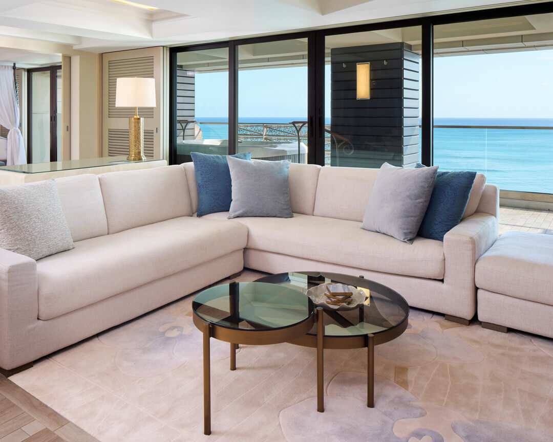 Living area with sectional sofa and large windows overlooking the ocean.