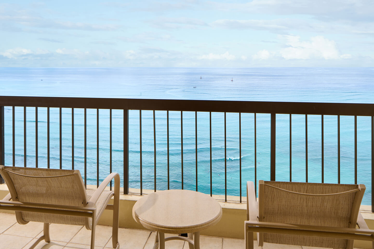 Balcony with table, chairs, oceanfront view.