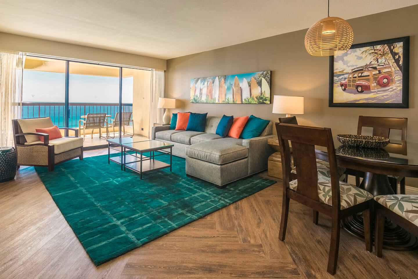 Living area with couch, coffee table, TV, dining area, balcony with ocean view.
