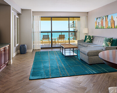 Living area with a couch, coffee table, TV, and balcony with ocean view.