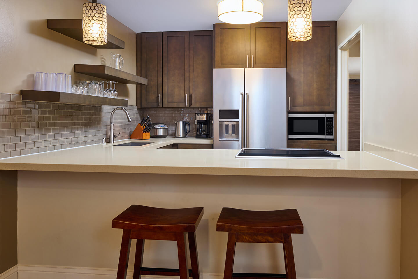 Fully-equipped kitchen with two barstools at a counter.