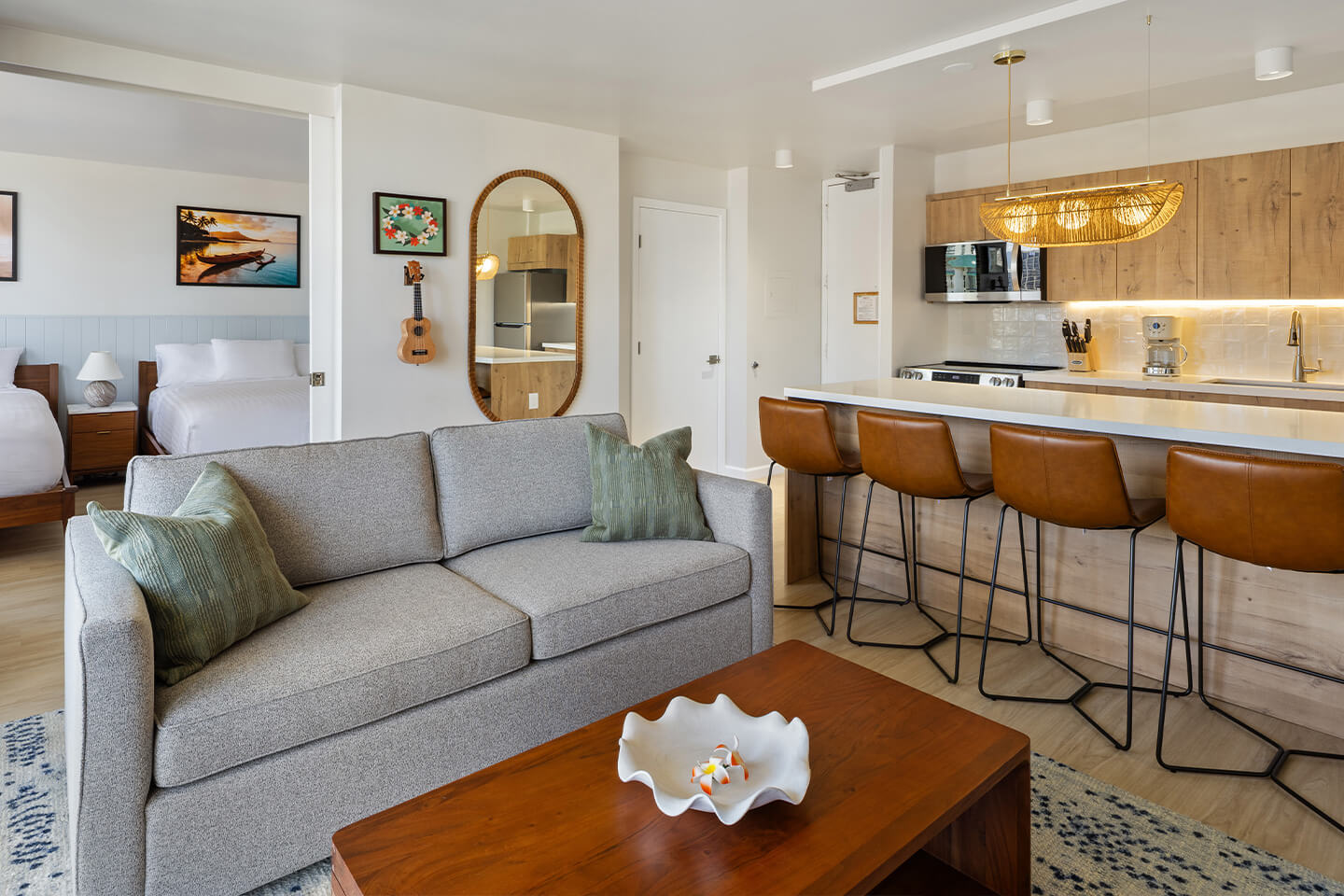 Living room with sofa and kitchen with barstools at a counter.