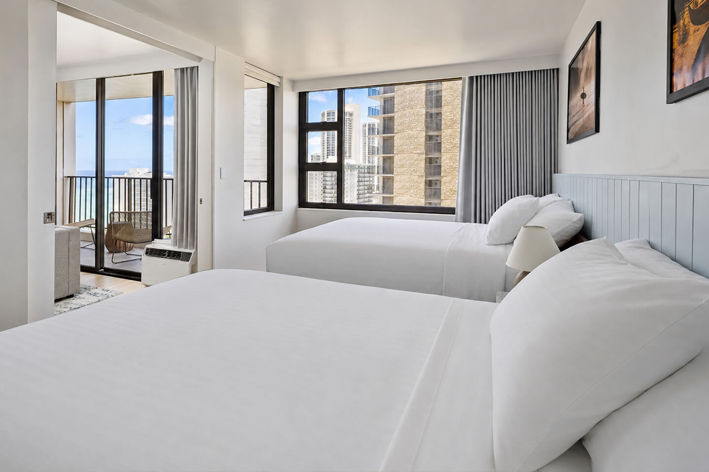 Bedroom with two queen beds and windows with city view.