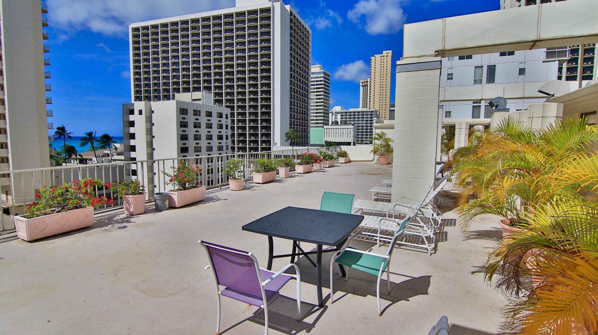 Rooftop sun deck with seating and views of the ocean.