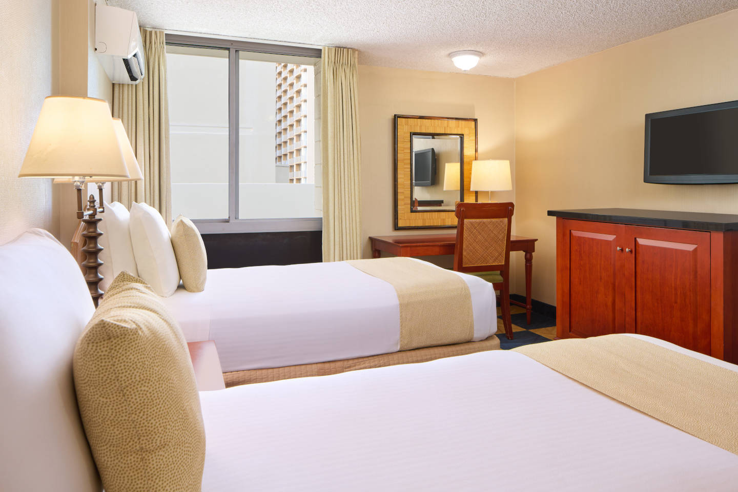 Room with 2 beds, a desk, chair, lamp, and TV.