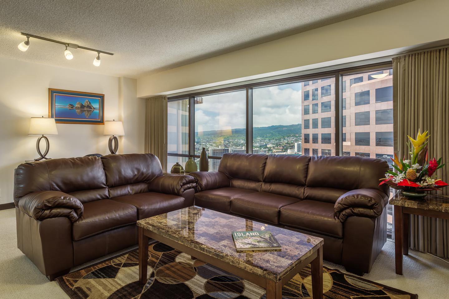 Living room with couches, coffee table, and large picture windows.