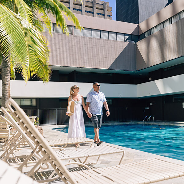 Couple walk along poolside.