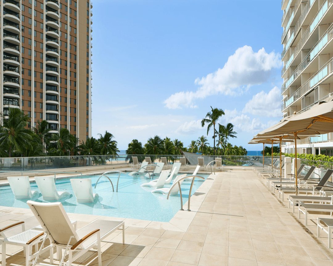 Sundeck and swimming pool with loungers in the water. 