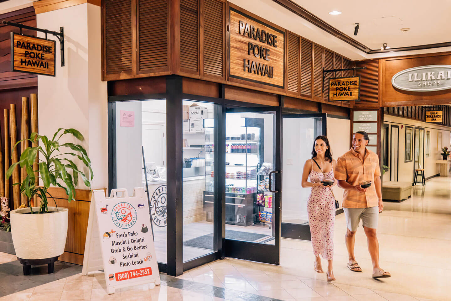 Couple waking out of Paradise Poke restaurant.