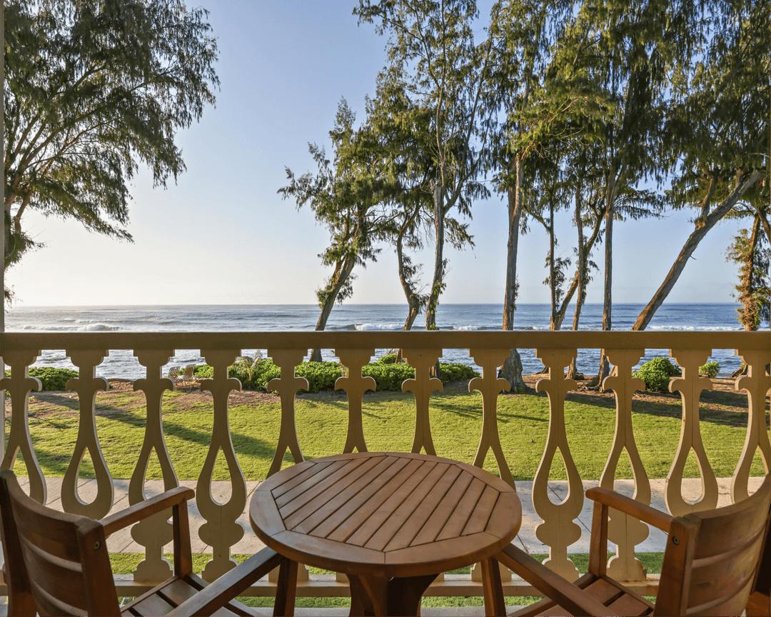 Balcony with two chairs and small table with view of the ocean.