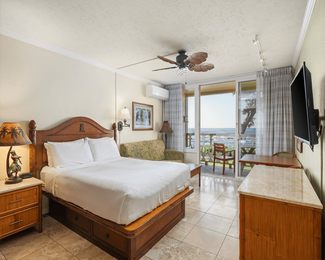 Guest room with sofa and balcony overlooking the ocean.