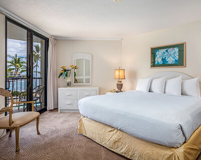 Room with a bed, lamp, and balcony with ocean view.
