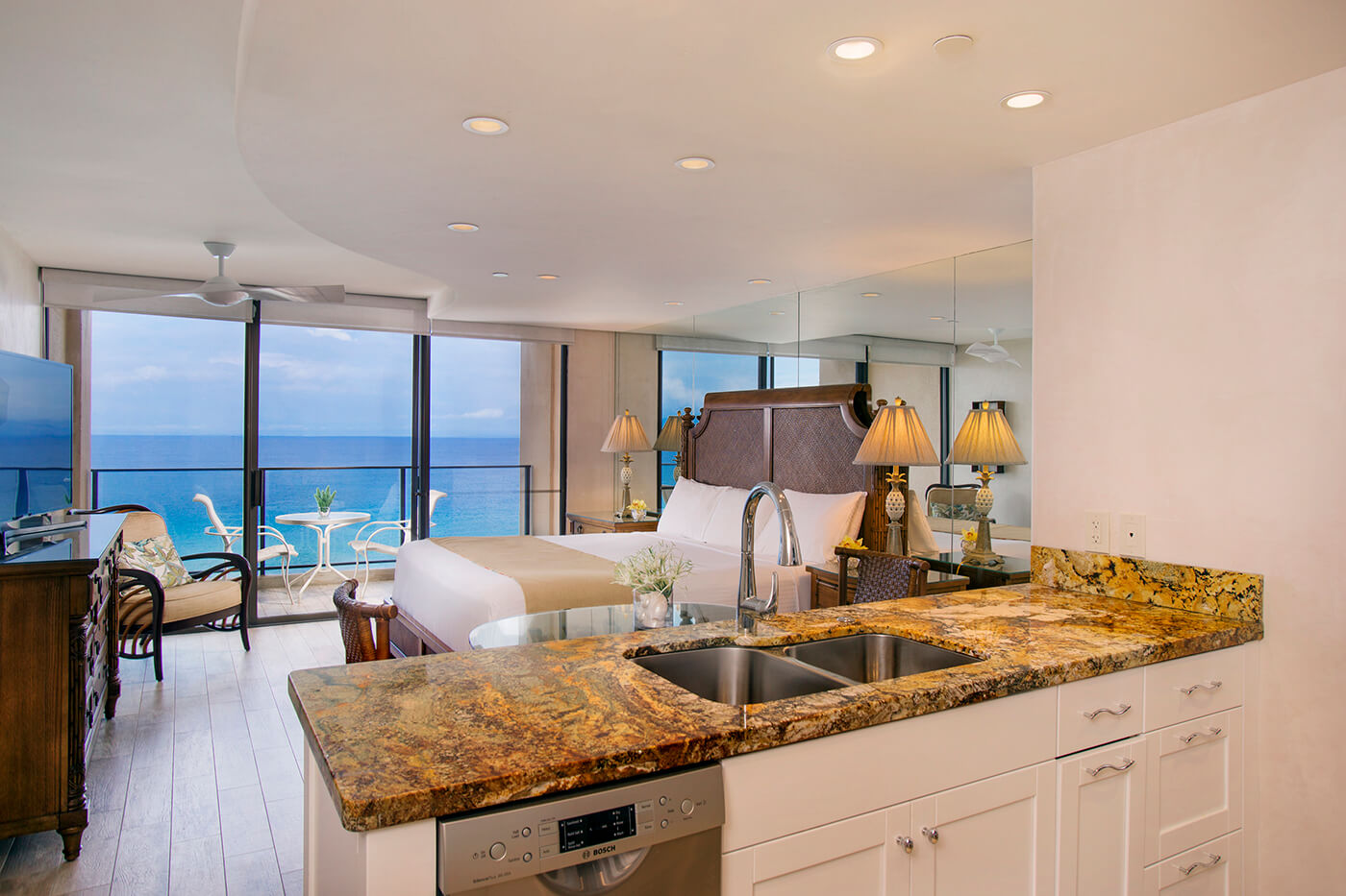 Room with a bed, dining area, kitchen, TV, and balcony with oceanfront view.