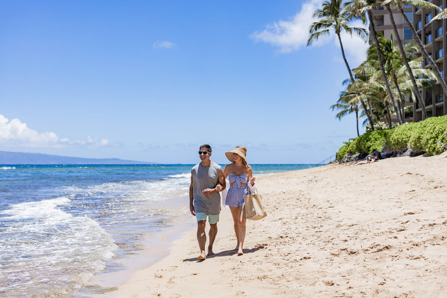 Couple walking along breachfront.