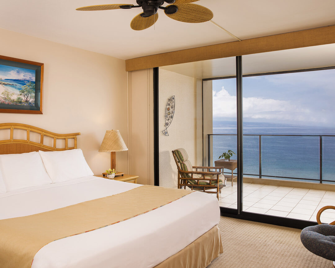 Room with a bed, and balcony with ocean view.