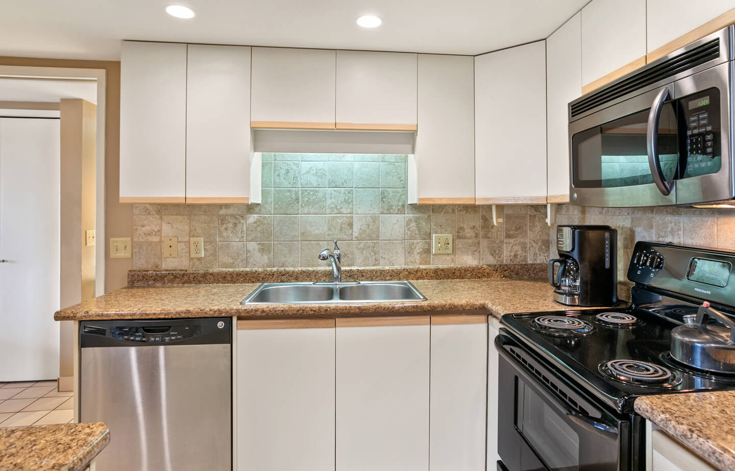 Kitchen with refrigerator, stove, microwave, sink, counters, and cabinets.