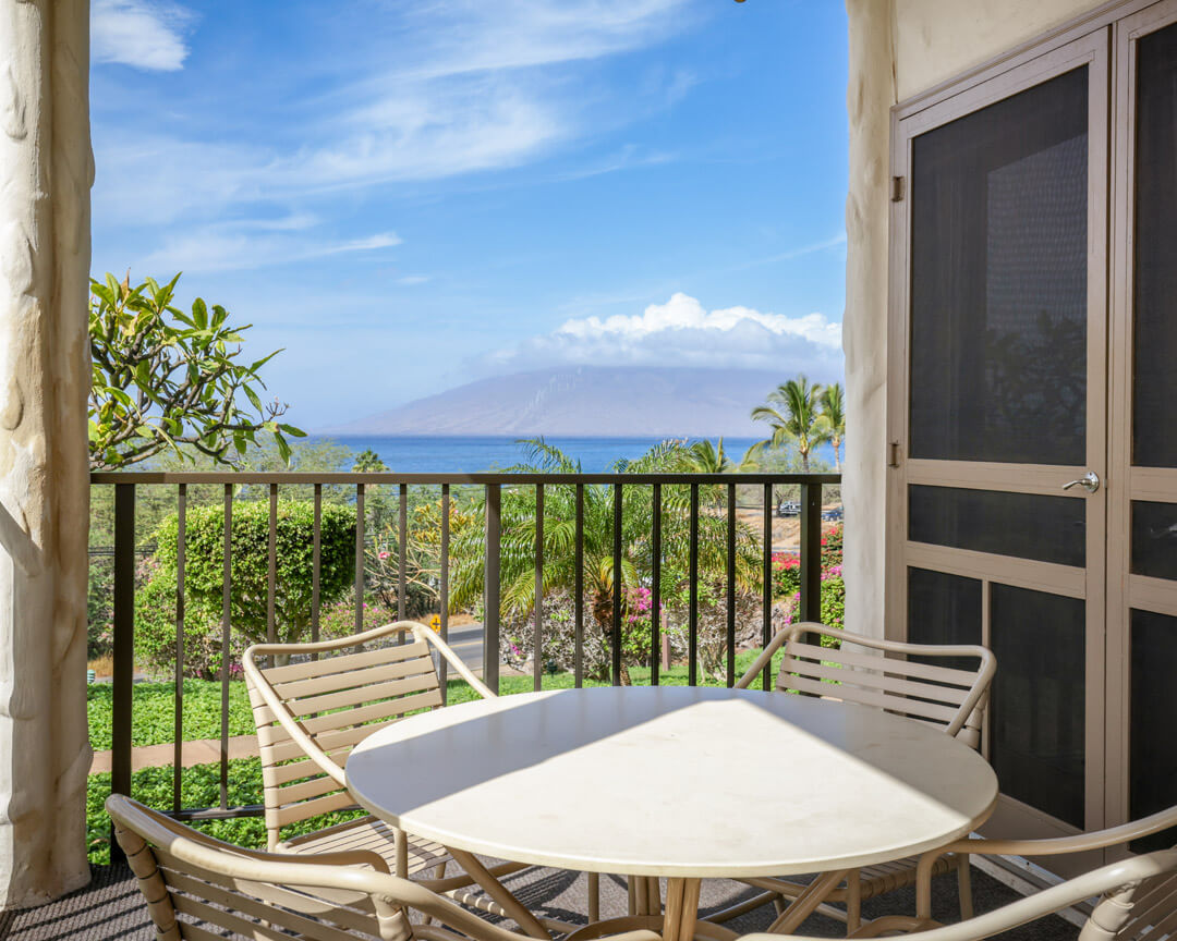 Ocean view from a lanai with seats and table.