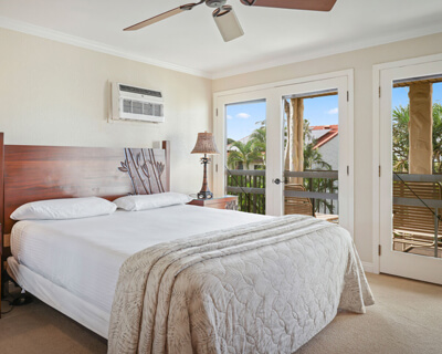 Room with a bed, nightstands, lamps, and balcony.