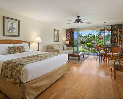 Room with a bed, couch, coffee table, lamps, dining area, and patio.