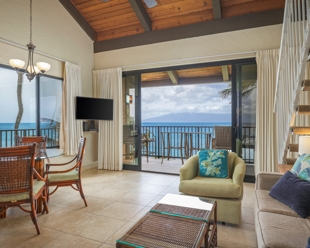 Living room with large windows and balcony overlooking the ocean.