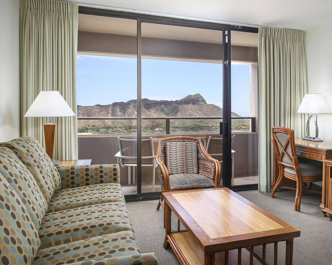 Living room with large windows and balcony overlooking Diamond Head.